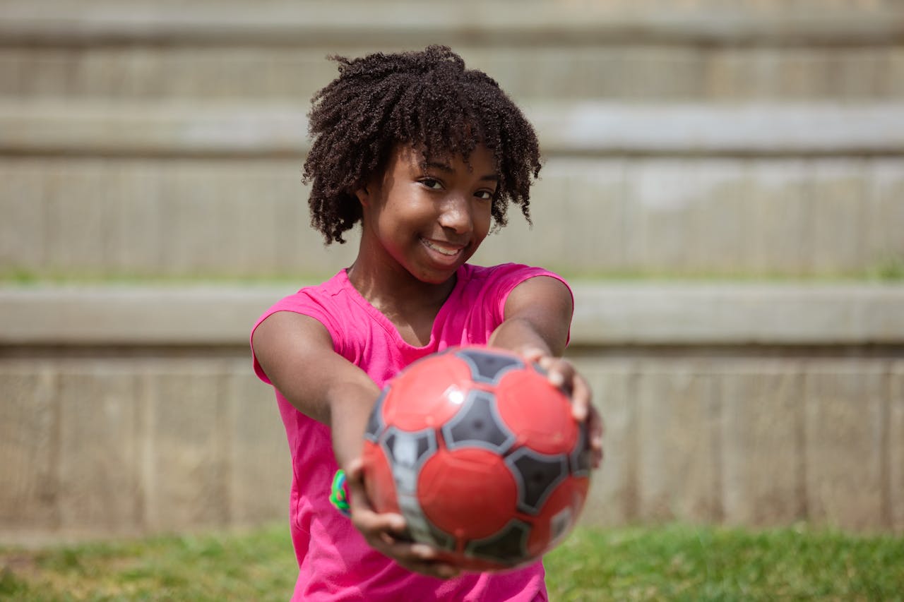 Child holding a football to camera